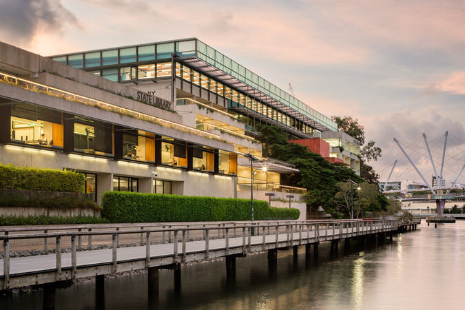 A photo at sunset of the Edge and State Library of Queensland buildings with the riverwalk in the foreground