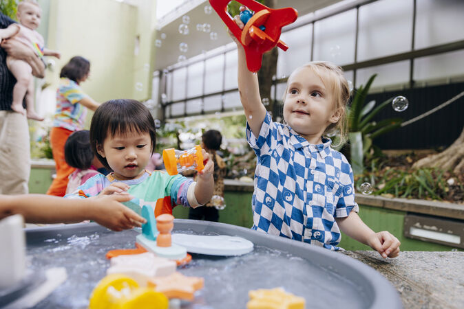 Children playing together outsite with bubbles and water.