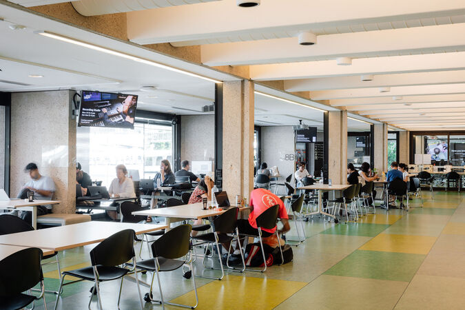 People working at table and chairs in a large room with a green floor