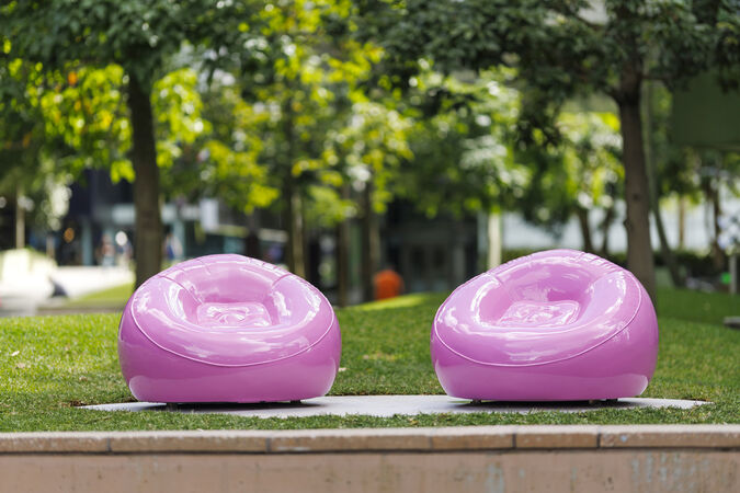 The artwork 'Pink Chairs' by Cj Hendry at State Library of Queensland with trees and lawn in the background