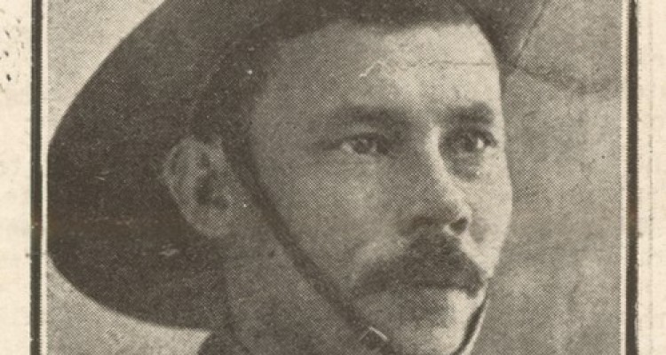 Soldier portrait, man in uniform, with dark hair and moustache, wearing hat with strap under the chin.