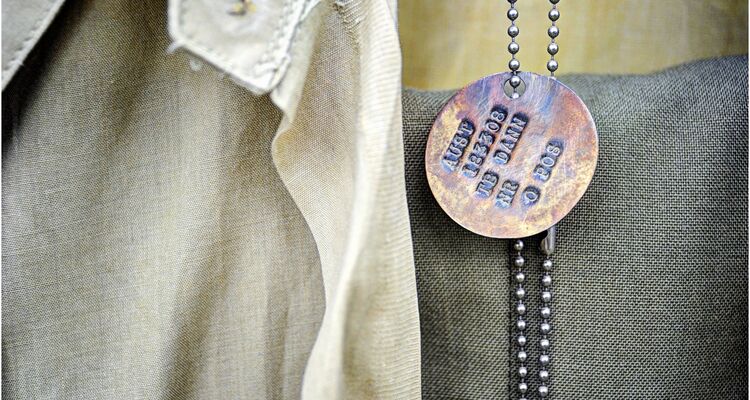 Circular identity disc on a chain. It reads 'AUST 183308 TB DANN NR O POS.'