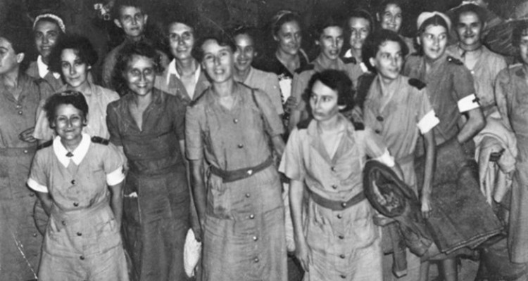 Group of 24 women in uniforms standing together. Some are smiling.
