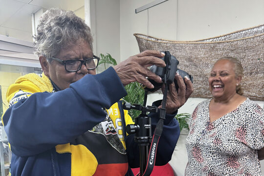 A photo of two women setting up a digital camera on a tripod