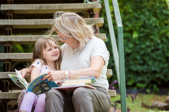Grandmother and granddaughter reading together outside