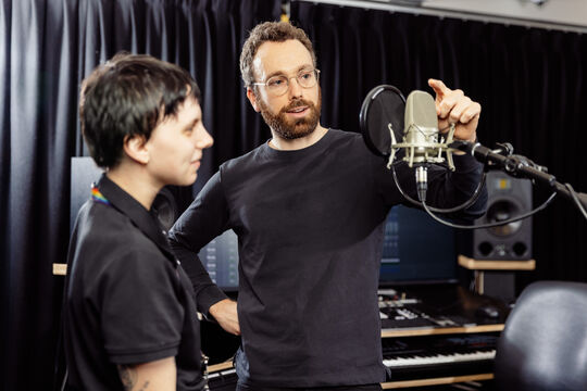 A recording studio induction in which Applied Creativity Staff demonstrate use of a microphone.