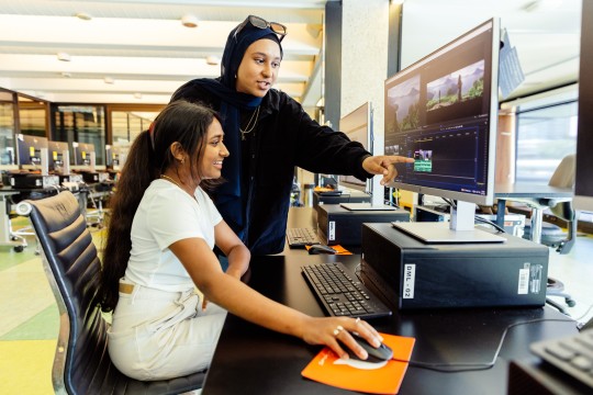 two young women use computer