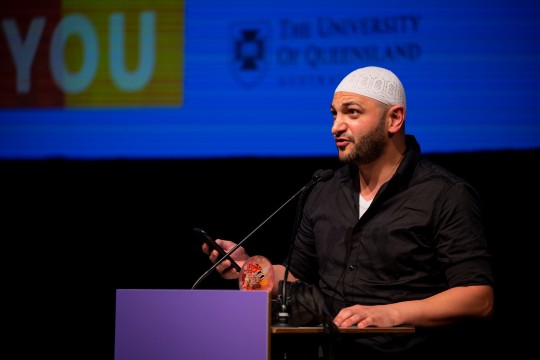 Michael Mohammed Ahmad stands behind a lectern on a stage