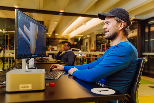 A photo of a man in a hat working on 3D modeling on a computer 