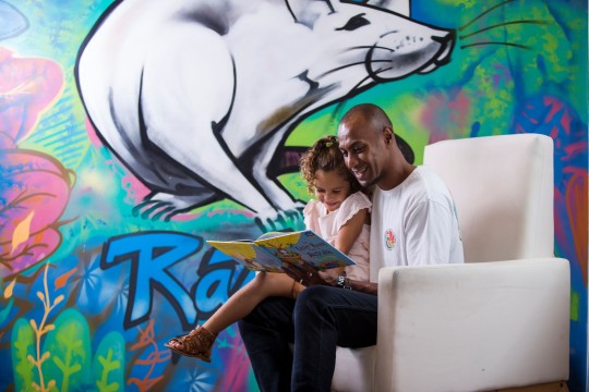 Father and daughter reading together in front of wall art