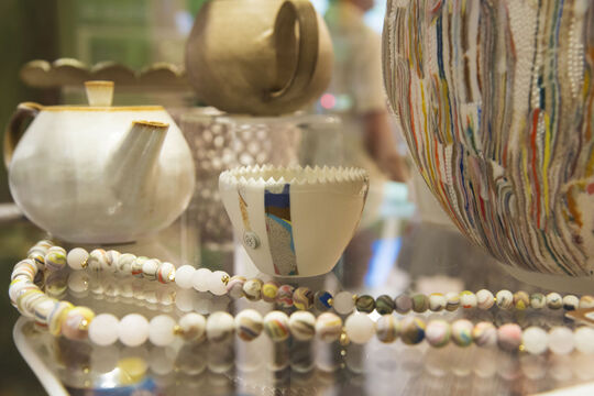 Hand crafted items displayed on a glass shelf.