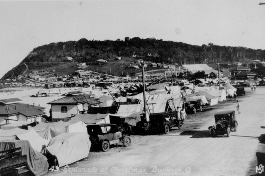 The Esplanade at Burleigh Heads crowded with tents and cars during Christmas holidays, 1932. Tents have been erected along the road and on the beach, turning the Esplanade in to a camping site.