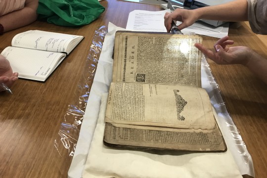 Staff member at conservation clinic with a book open and spotlight shining on an article of text