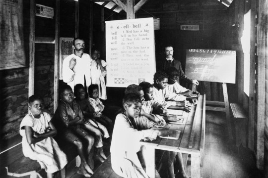 Two male teachers in a classroom with Aboriginal children sitting at desks