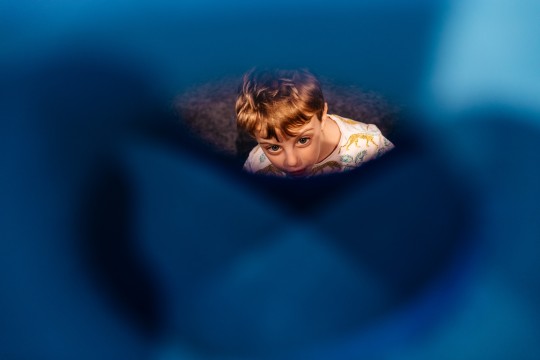 Child looking through window of foam structure