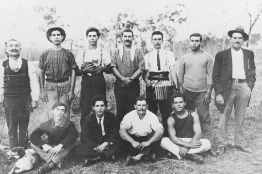  In the back row, third from the left, is Minas Logothetis holding a kitten. Fifth from the left is Anargeroo Megaloconomos holding an accordion. In the front row, second from the left, is Nicholas Logothetis. Fourth from the left is Peter Motis. All except three people of this gang were from the Greek island of Kythera (Description supplied with photograph).