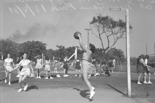 One woman catching a ball in basketball game New Farm Park, 1951.