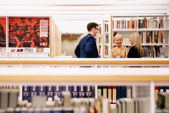 People chatting between the shelves at the State Library.
