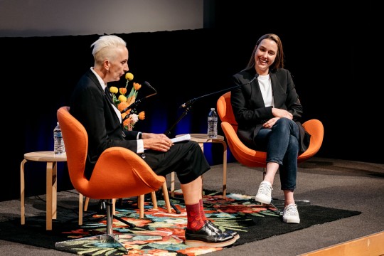 Two women seated and talking on stage.