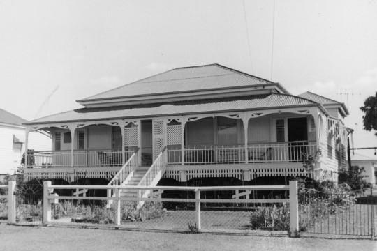 B&W image of single storey, weatherboard house with a corrugated iron roof and a chain link and timber fence at Maryborough.