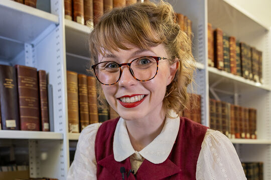 Young woman wearing glasses in front of bookcase
