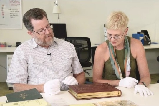 Researchers Matthew Wengert and Louise Martin-Chew explore an item from the collections of the John Oxley Library.