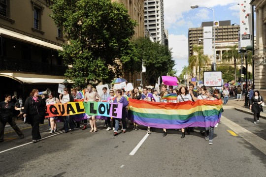 Pride colours and Equal Love banner lead the way in the rally in George Street, Brisbane