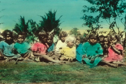 Coloured image of Pastor Schwarz's daughter sitting with several First Nations children c.1902