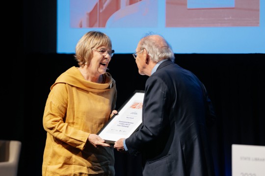 Woman accepting a framed award on stage.