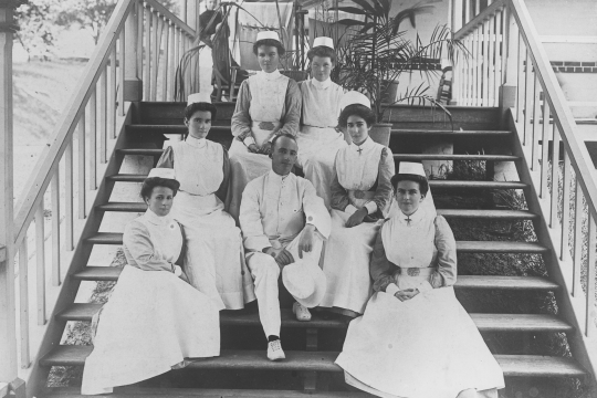 A black and white photograph of six Nurses and one doctor sitting on the steps at the Royal Brisbane Hospital. 