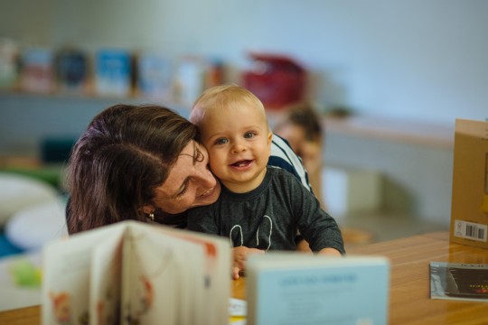 A baby and mother cuddling in State Library Queensland's The Corner with books in the foreground