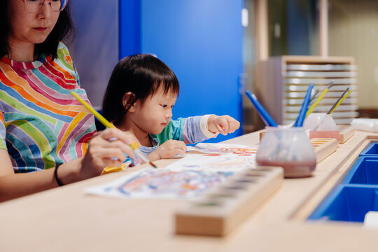 Woman and young child painting together.