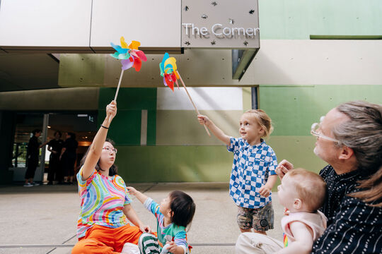 Adults and children playing outside with pinwheels.