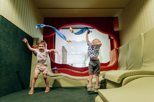 Two small children jumping and playing with a ribbon in The Corner.