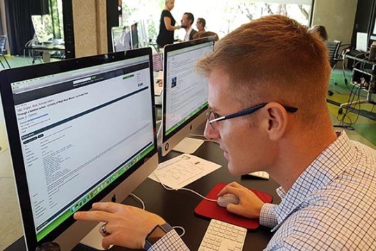 A young man examines a computer screen