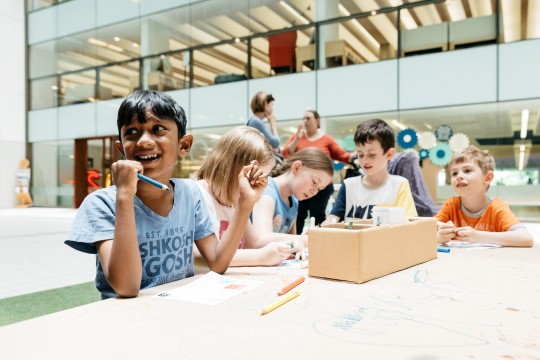 Kids working around a table at the Summer Festival, State Library Queensland