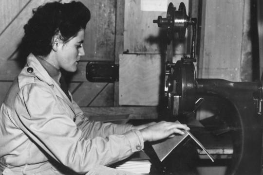 young woman in light coat operates machinery as part of the women's land army 