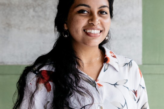 Photo of a young woman smiling and wearing a floral shirt