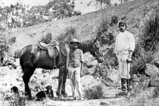 Portrait of W. B. Slade and an aboriginal stable boy on Cockatoo Creek Station, Queensland, 1866. A cropped version of this photograph appeared in The Queenslander, 7 July 1932, p. 27 with the caption: 'Mr W. B. Slade, his stable boy, favourite horse and dogs'.
