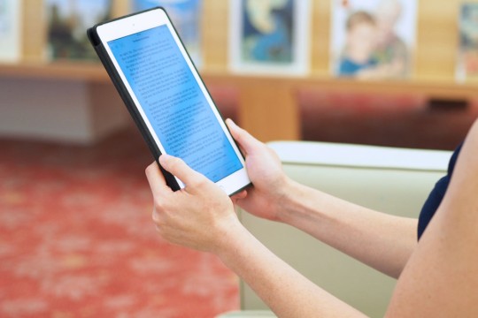 Person reading an ebook on an electronic tablet.