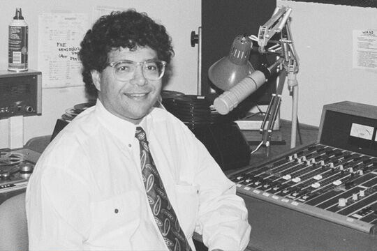 Black and white photo of Wayne Coolwell sitting at a radio desk at ABC Studio, New York City.