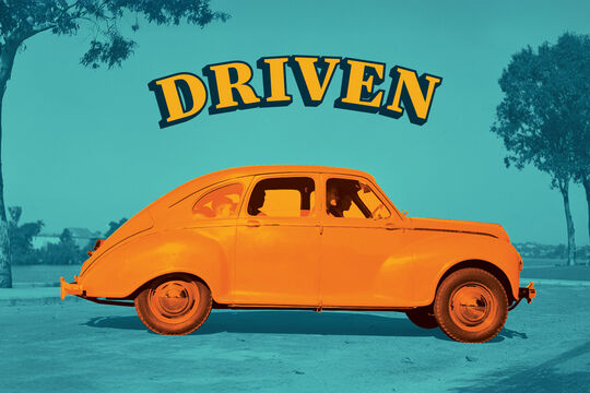 A vintage car is coloured in bright orange against a teal background with silhouetted trees. Above the car, the word “DRIVEN” appears in bold, arched lettering with a navy shadow.