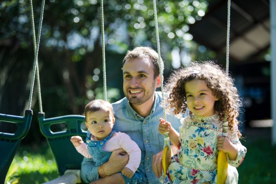 Father and daughters playing on swing set