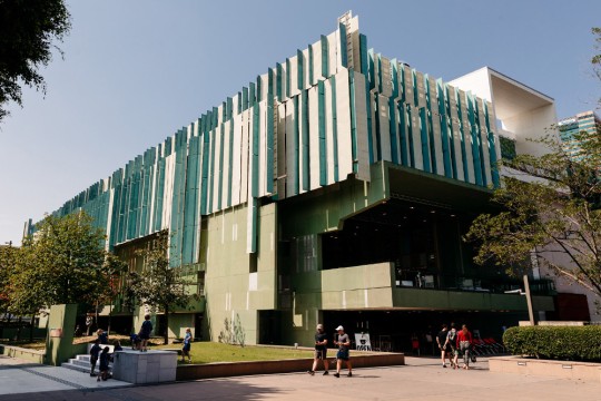 Exterior view of State Library building during the day with people walking in front of it. 