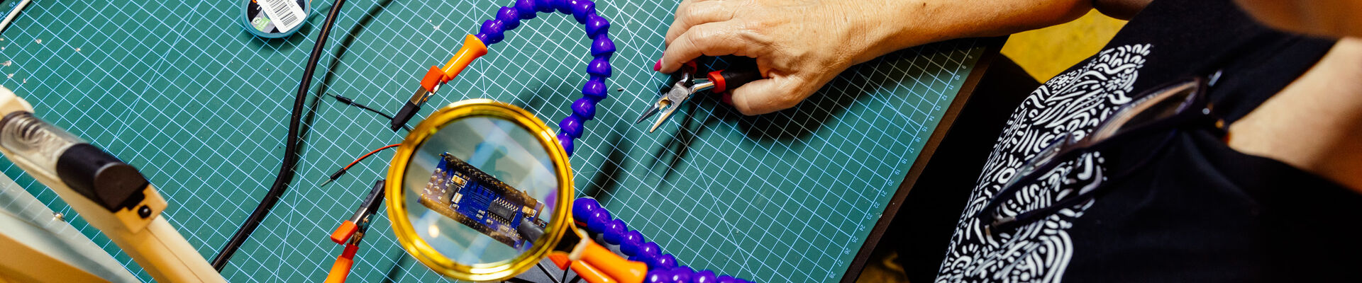 Someone soldering at an electronics bench 