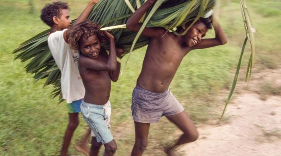 Boys carrying a bundle cabbage palm leaves