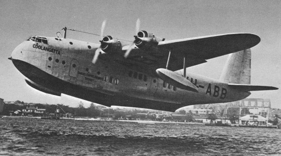Black & while photo of a large plane taking off about 1938