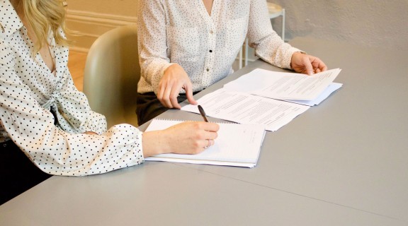 Two people sitting at a desk and signging documents.