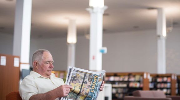 Man reading newspaper in the Caboolture public library.
