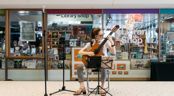 A volunteer musician performing outside the State Library Shop